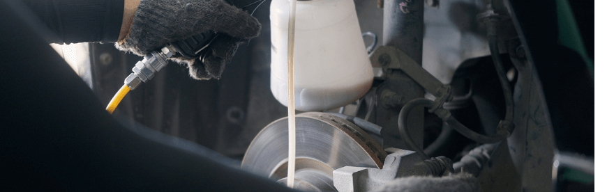 Are Fluid Flushes Really Necessary in Cleveland Heights OH with Swedish Solution; closeup image of mechanic performing a fluid flush on brakes on a vehicle in shop