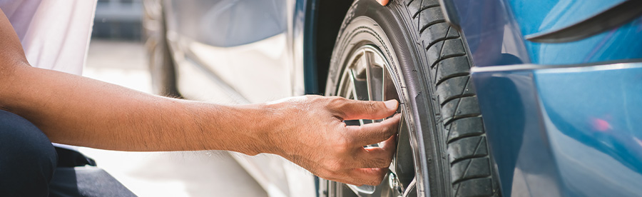 A male auto technician checking tire in an auto garage. Concept image of “7 Spring Car Care Tips for Your European Cars” | Heights Swedish Solutions in Cleveland Heights, OH.